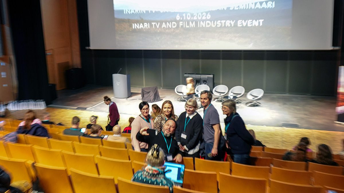 Joukko ihmisiä ottaa ryhmäselfietä auditoriossa